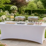 Eckiger Banketttisch mit weißer Stretchhusse und Buffetaufbau im Garten